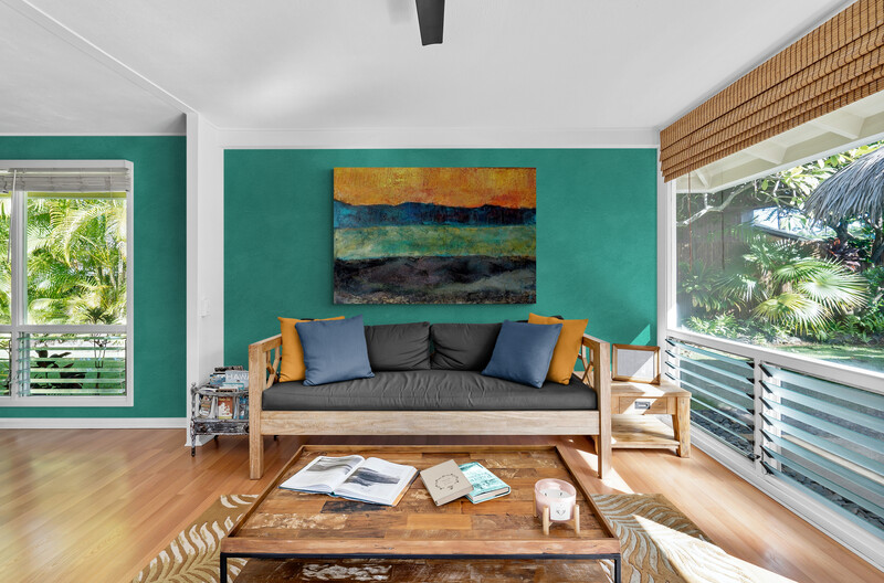 Raum mit Sofa, Holzboden und Fenstern an der Seite. DIe Wand hinter dem Sofa ist petrolfarben. An dieser Wand hängt das oben beschriebene abstrakte Landschaftsbild  mit 4 horizontalen Farbflächen